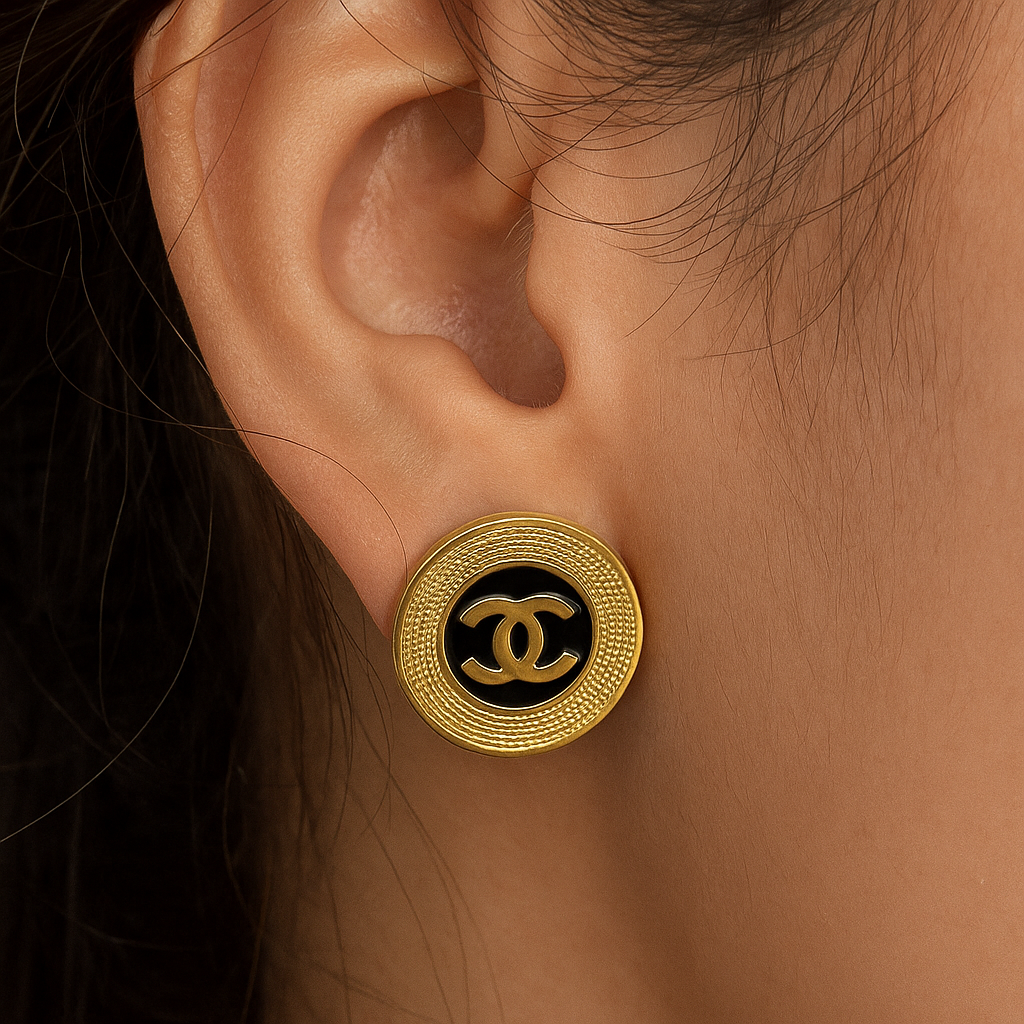 Gold Chanel earring on an ear with a dark background