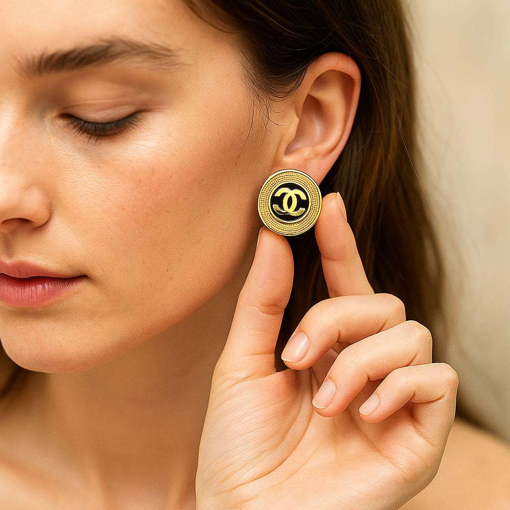 Woman wearing a gold chanel earring with a brand logo