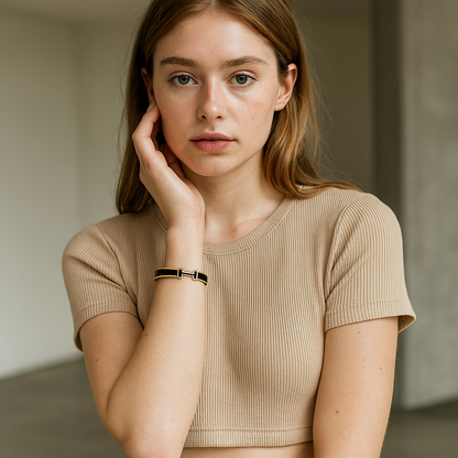 Woman wearing a beige ribbed top with 18K gold Hermes Black bangle bracelet.