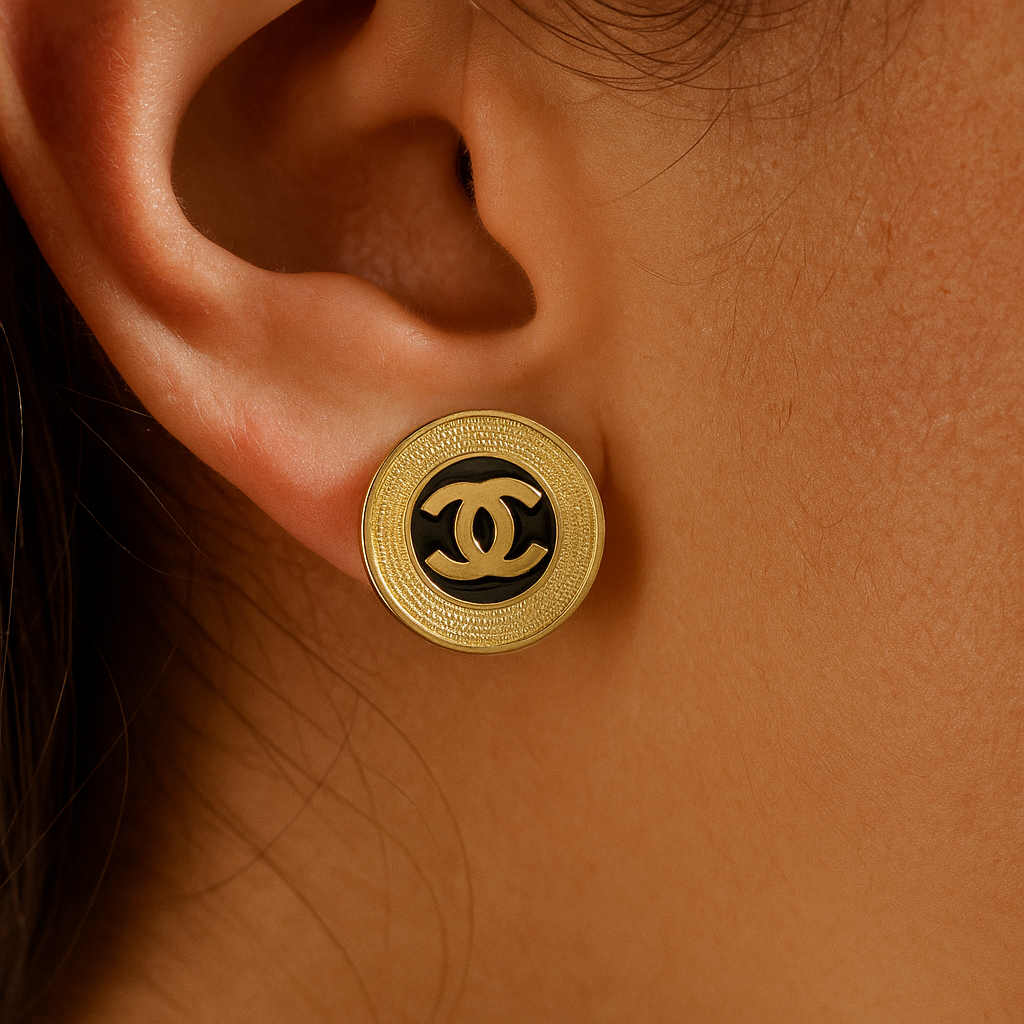 Gold earring with black center worn on an ear