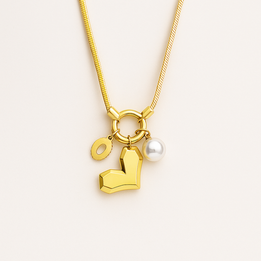 Gold necklace with heart and pearl charm on a light beige background