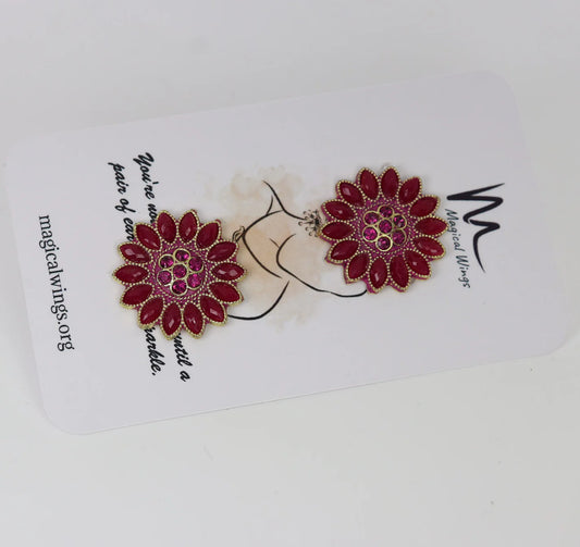 A pair of red floral stud earrings displayed on a white card with the brand name 'Magical Wings' written above.